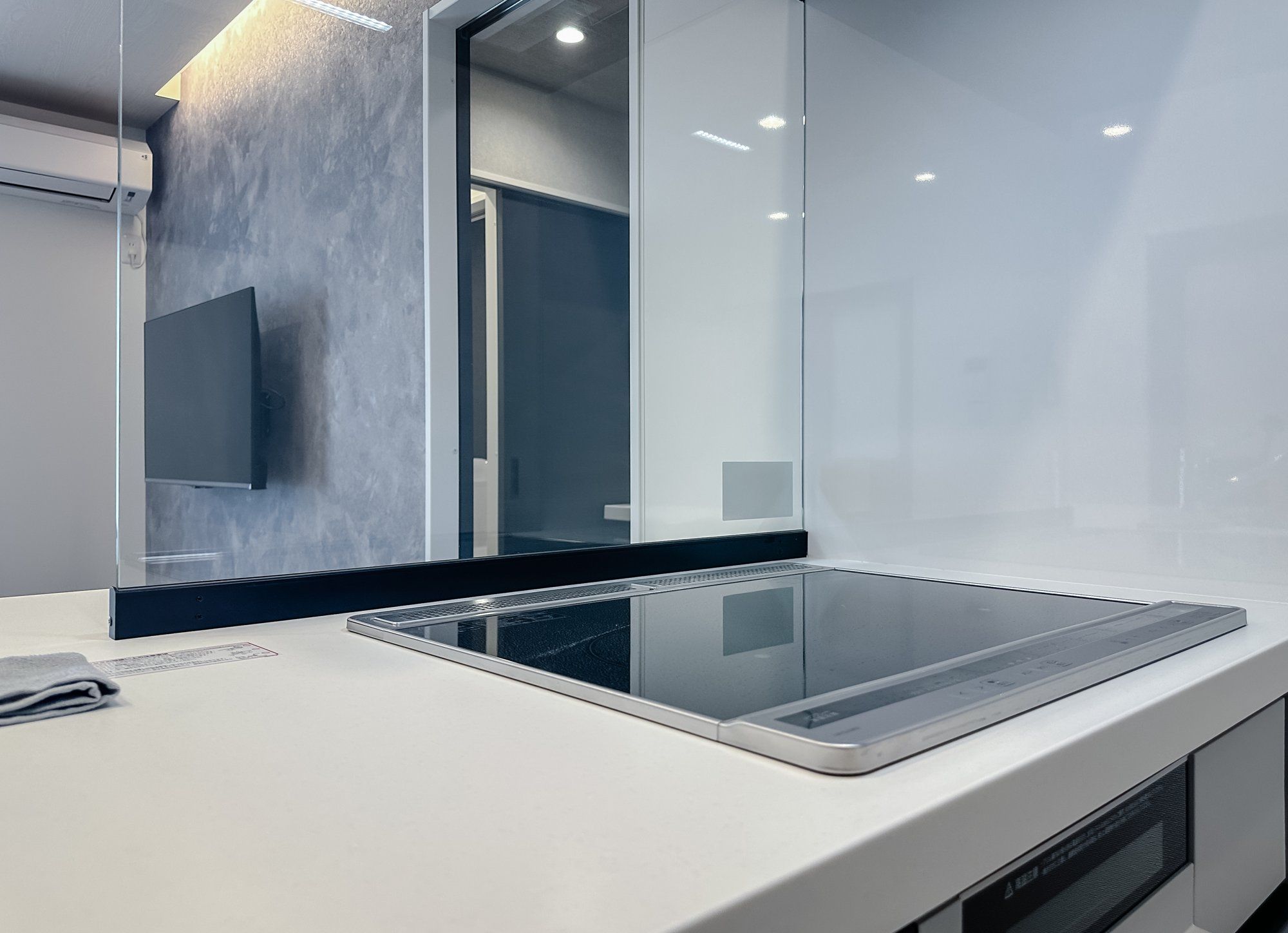 A modern kitchen with a sleek countertop, a built-in oven, and a large mirror.
