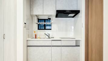 A modern kitchen with a built-in oven, a range hood, and a window above the sink.