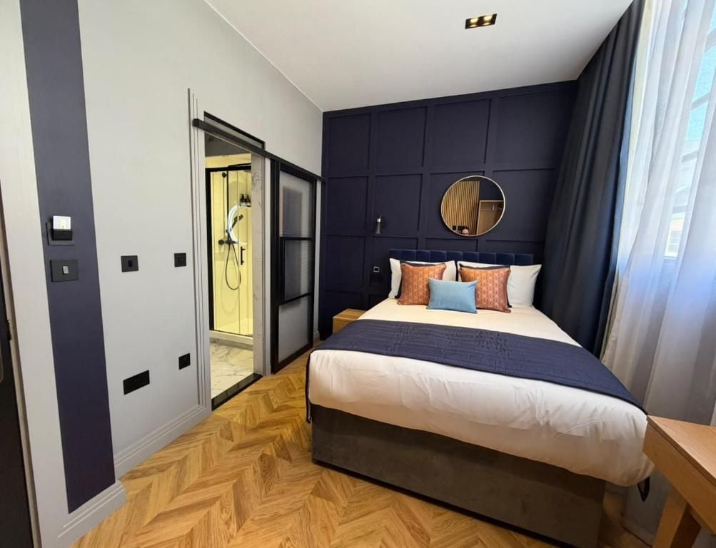 A modern hotel room with a large bed, a round mirror, and a view of a bathroom.