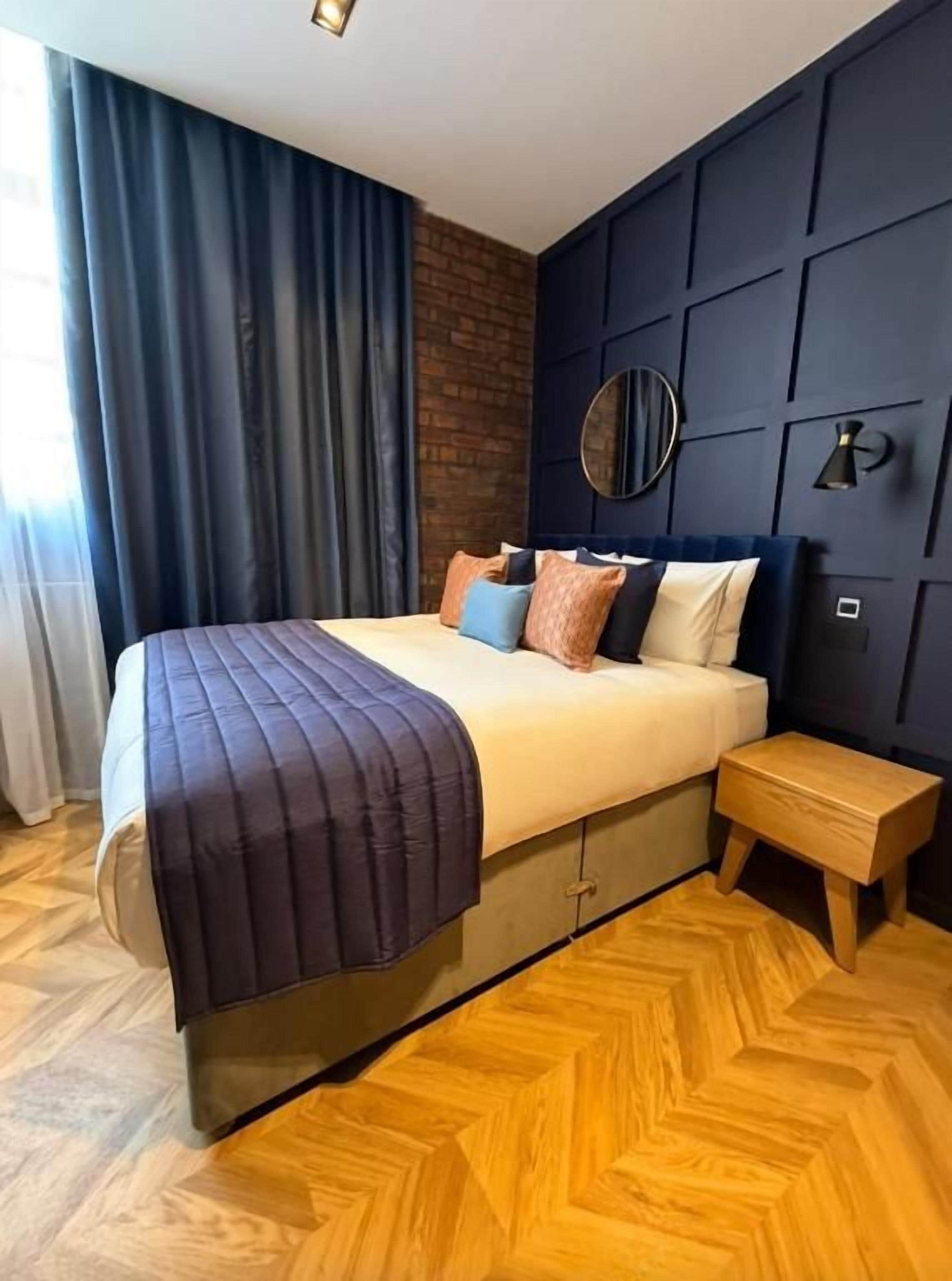 A modern bedroom with a bed, bedside table, and a wall-mounted mirror.