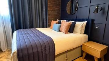 A modern bedroom with a bed, bedside table, and a wall-mounted mirror.