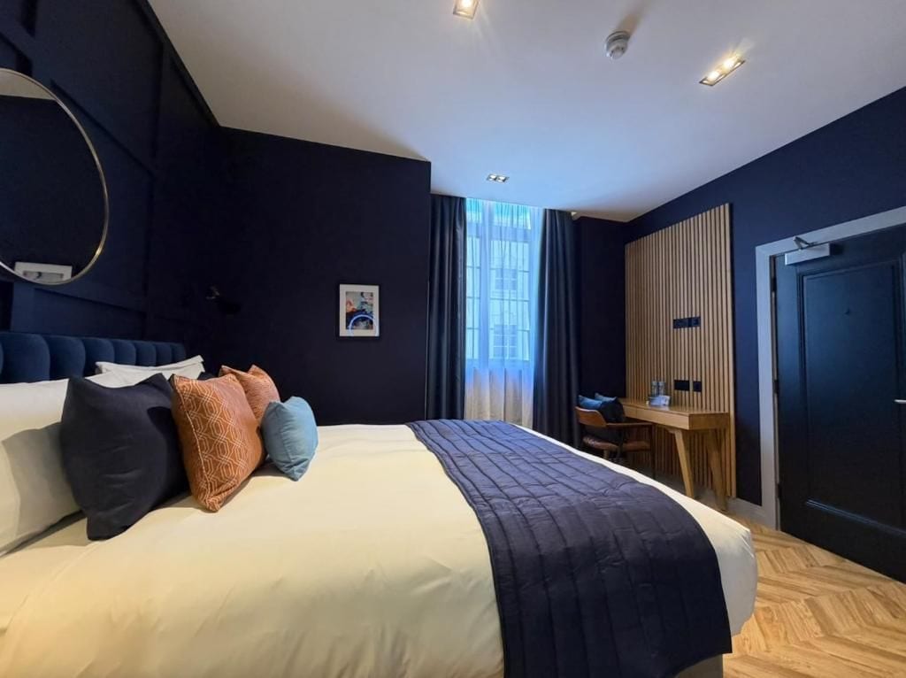 Una habitación de hotel moderna con una cama grande, un escritorio y un armario.
