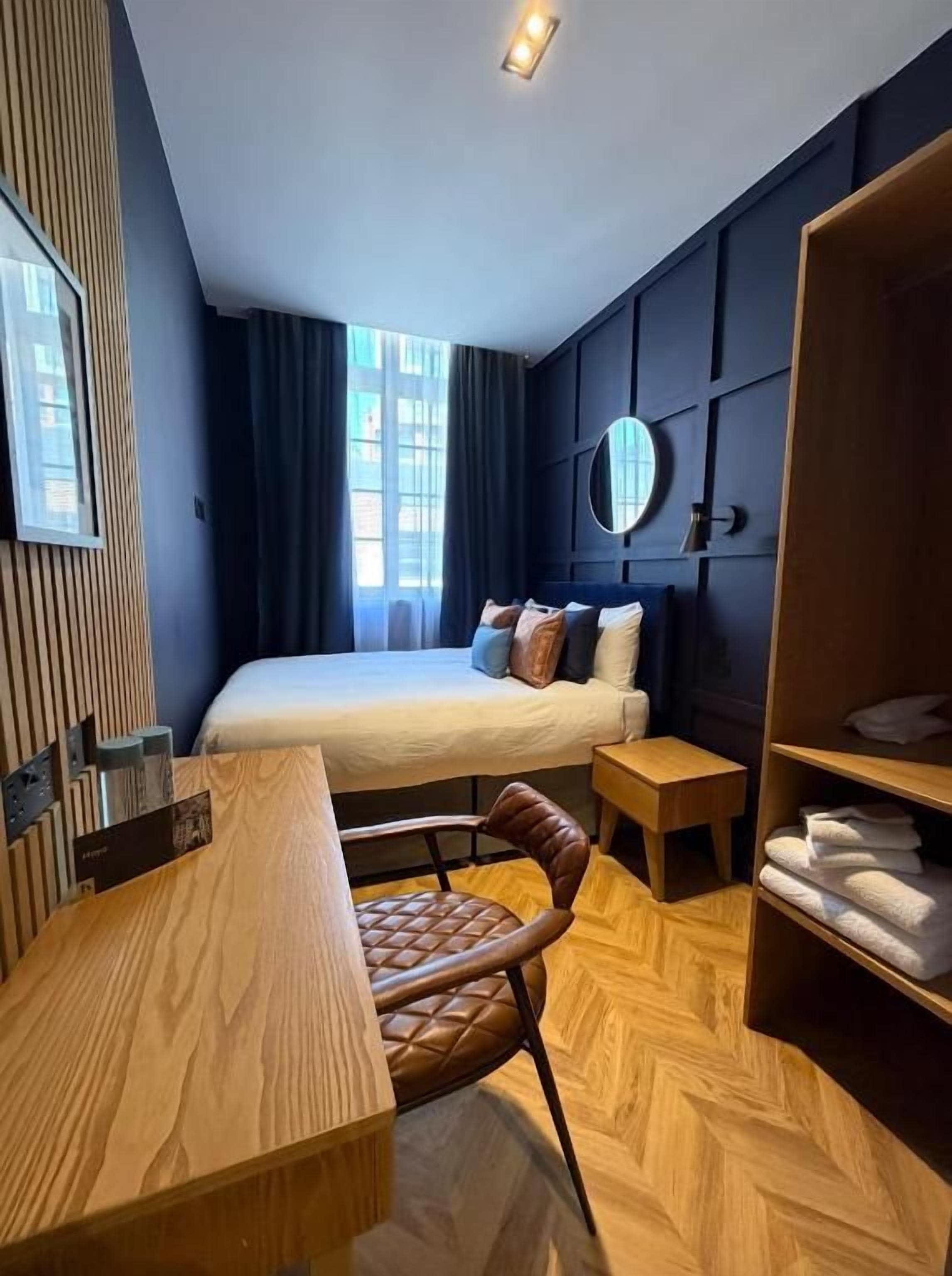 Camera d'albergo moderna con un grande letto, una scrivania in legno, una sedia, un tavolino e un armadio.
