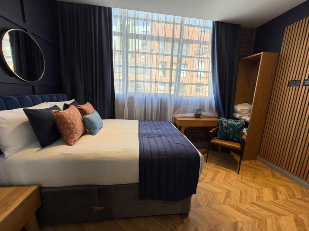 Camera d'albergo con un ampio letto, pavimento in legno, una scrivania e una finestra vista edifici.