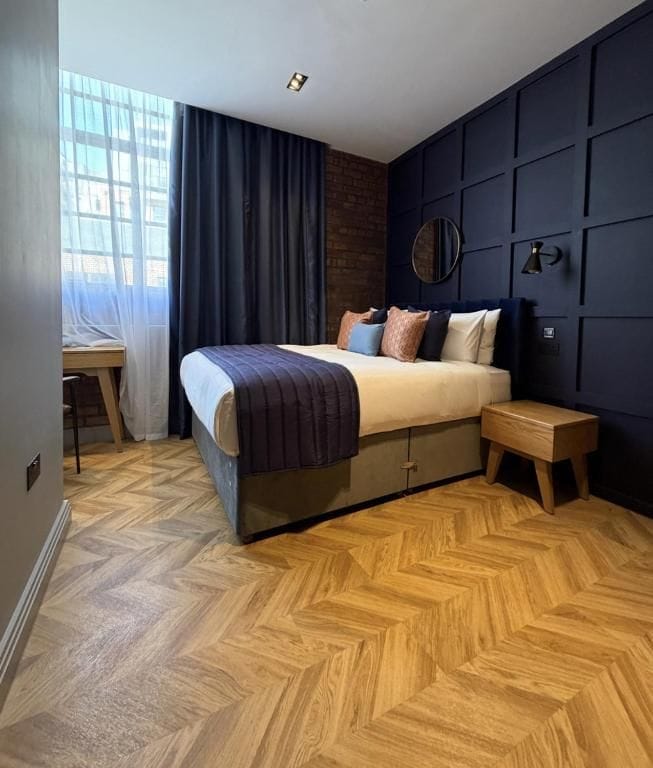Un dormitorio con cama, mesita de noche y escritorio con silla.