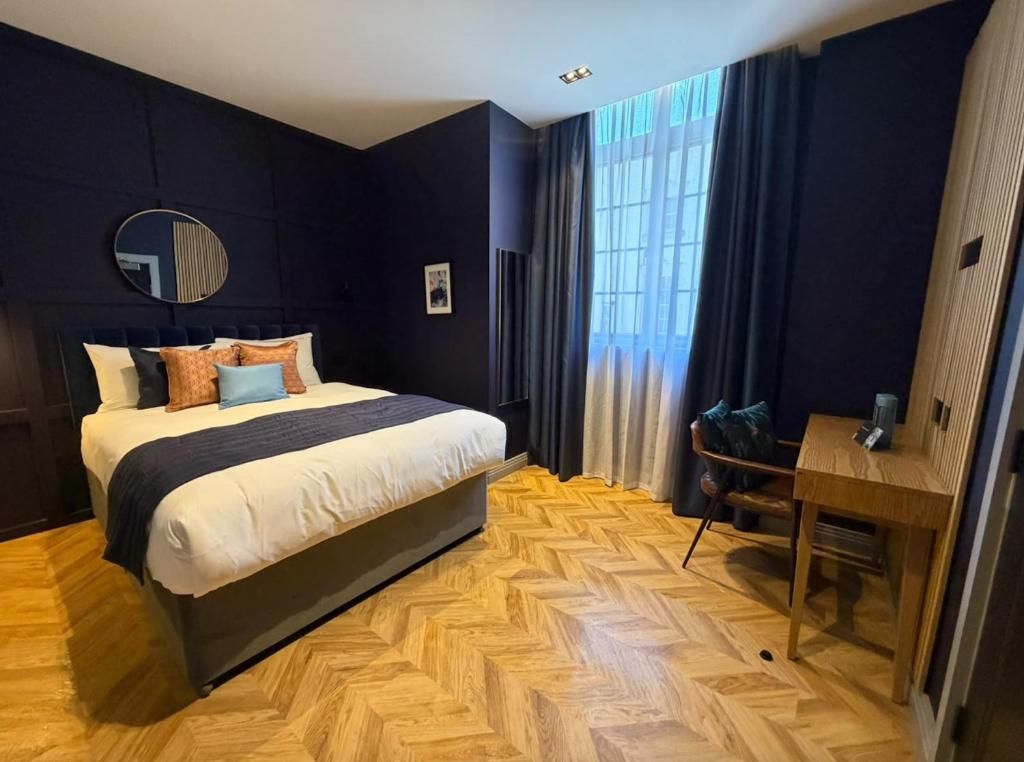 Camera d'albergo con un letto grande, una scrivania, uno specchio e una finestra con tende.