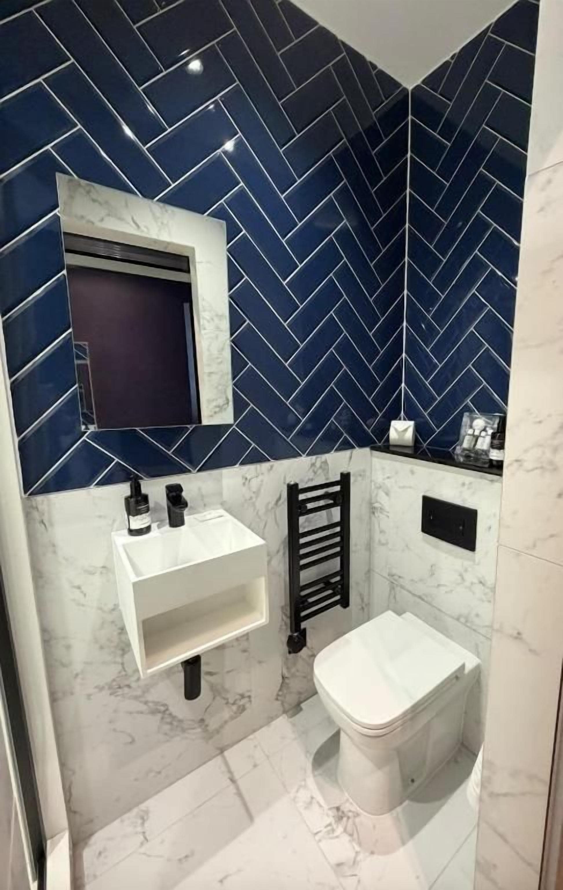 Un baño con inodoro blanco, lavamanos y un perchero para toallas.