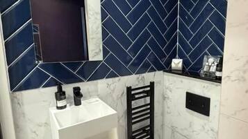 Un baño con inodoro blanco, lavamanos y un perchero para toallas.