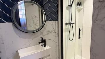 Un bagno moderno con cabina doccia in vetro, uno specchio rotondo e un pavimento in marmo.