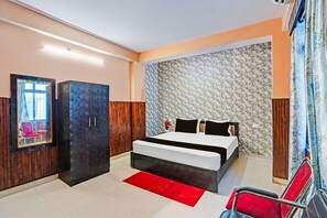 A bedroom with a bed, a wardrobe, a mirror, and a red rug. - Deluxe Room The Suncity Hotel (Patna)