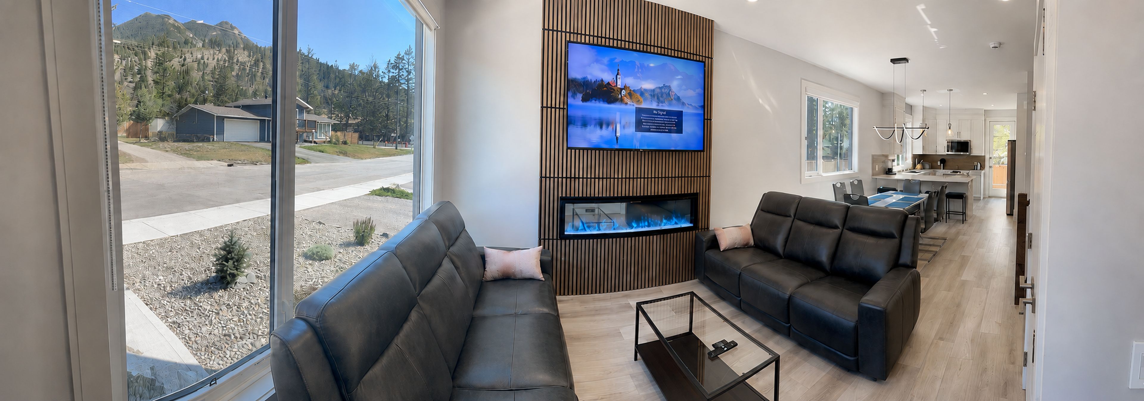 A modern living room with a large TV, two sofas, and a glass coffee table.