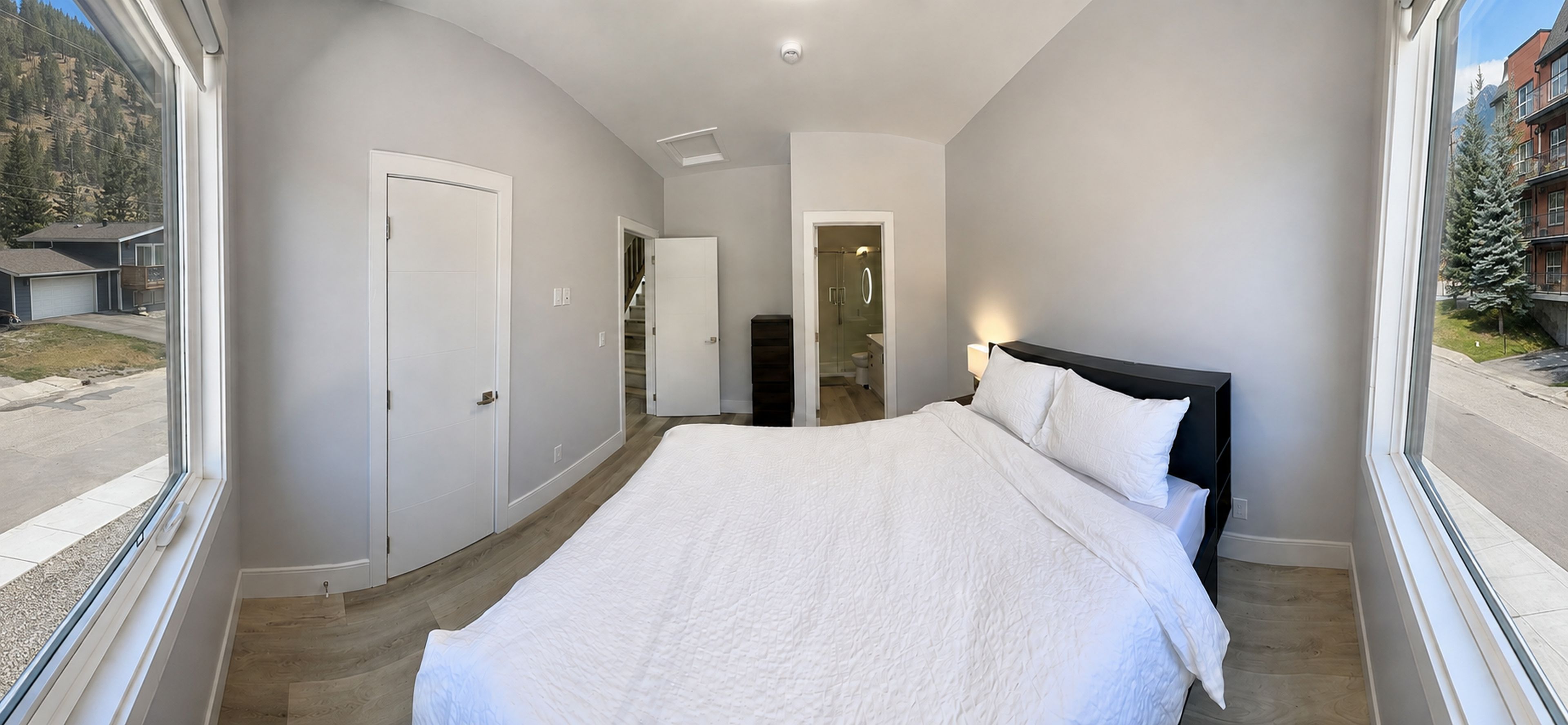 A bedroom with a bed, a door, and a view of the outside.