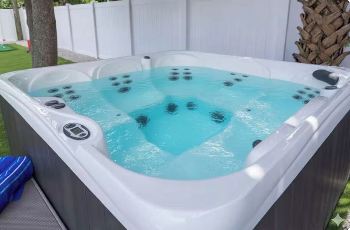 A hot tub with multiple jets, surrounded by a white fence and a palm tree.