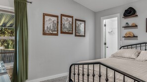 Ein Schlafzimmer mit einem Bett, einer Tür und zwei gerahmten Bildern an der Wand.