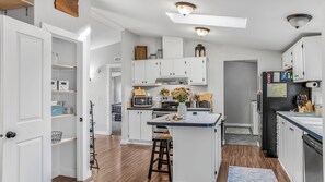 A modern kitchen with white cabinetry, a central island, and a microwave. - Hidden Haven | Made for Families + Outdoor Retreat (Molalla)