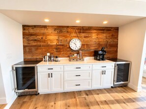 A kitchen with a wooden wall, a clock, and a coffee maker.