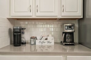 Eine Küchenarbeitsplatte mit einer Kaffeemaschine, einer Keurig und einem Schild mit der Aufschrift 'Coffee Bar'.