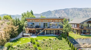 A two-story modern house with a deck, outdoor seating, and a view of mountains. - Wapato Waters-your Manson getaway-lakefront, family-friendly, dock, and hot tub. (Manson)