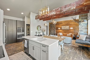 A modern kitchen with a central island, built-in appliances, and a rustic wooden ceiling. - Wapato Waters-your Manson getaway-lakefront, family-friendly, dock, and hot tub. (Manson)