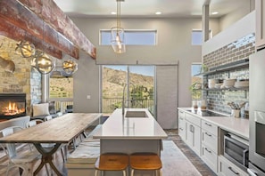 A modern kitchen with a central island, a fireplace, and a view of a mountainous landscape. - Wapato Waters-your Manson getaway-lakefront, family-friendly, dock, and hot tub. (Manson)