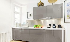 Een moderne keuken met een roestvrijstalen spoelbak, een waterkoker, een broodrooster en een schaal met fruit.