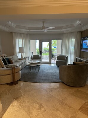 A spacious living room with a sofa, two armchairs, a coffee table, and a television. - Oceanfront 3BR at the Ritz-Carlton Club: Beach Walkout & Handicap Accessible (Nazareth)
