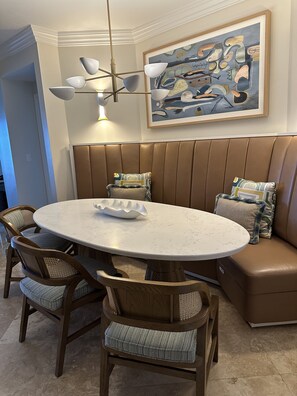 A dining area with a round table, wooden chairs, a bench, and a modern chandelier. - Oceanfront 3BR at the Ritz-Carlton Club: Beach Walkout & Handicap Accessible (Nazareth)