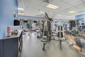 A gym with various exercise machines, a mirror, and a counter with a pink cup. - Spacious 4BR Retreat | Pool | Disney & Universal (Kissimmee)