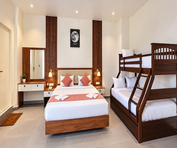A hotel room with a large bed, a bunk bed, a bedside table with a lamp, a mirror, and a framed picture on the wall. - Super Deluxe Room V Stays (Chittoor)