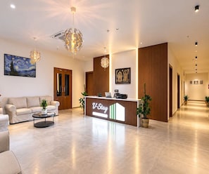 A hotel reception area with a modern design, including a reception desk, a painting, and a chandelier. - Super Deluxe Room V Stays (Chittoor)