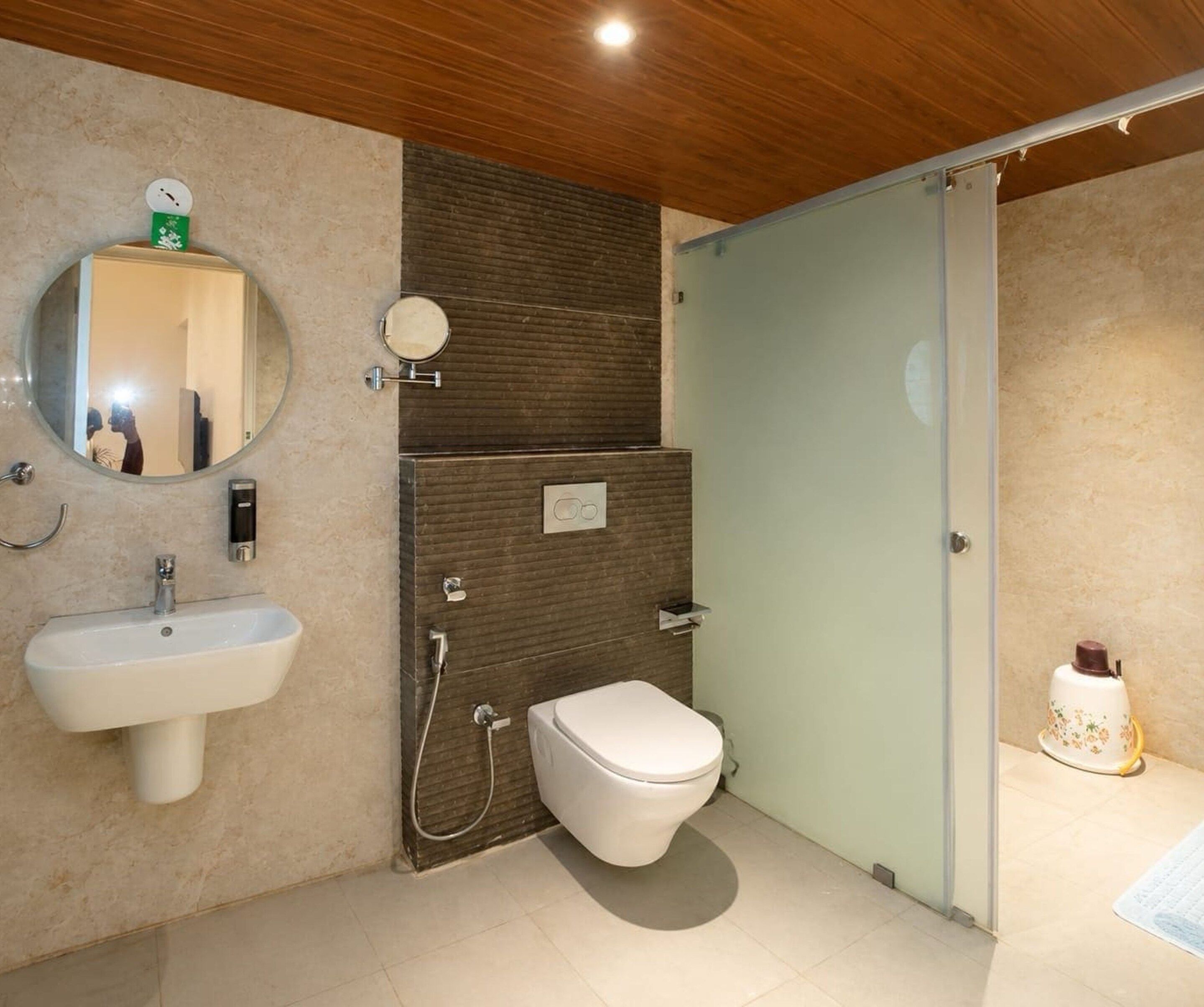 Et badeværelse med vask, spejl, toilet og brusebad.