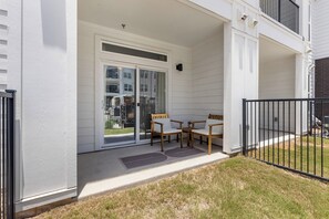 Une terrasse couverte avec une table et des chaises, une porte-fenêtre coulissante et un petit espace jardin.