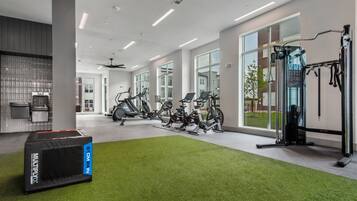 A modern gym with stationary bikes, a treadmill, and a weight machine.