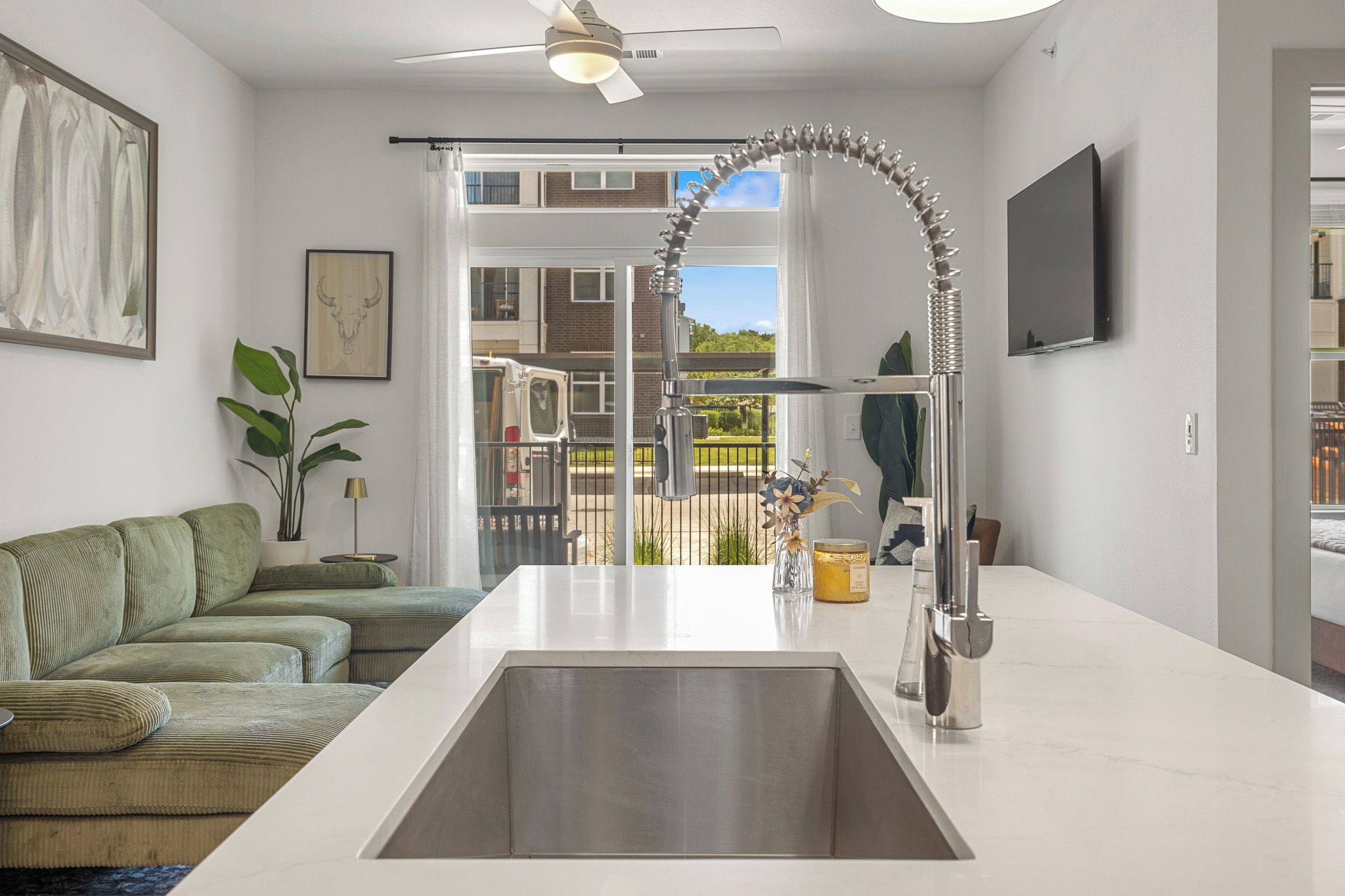 A modern kitchen with a central island, a ceiling fan, and a view of the outside.