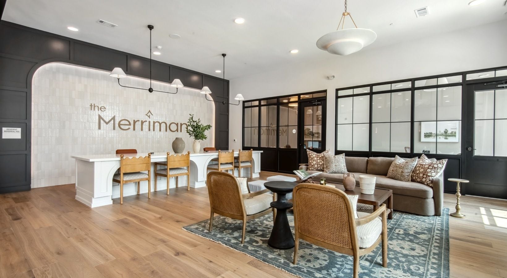 A modern hotel lobby with a reception desk, seating area, and large windows.