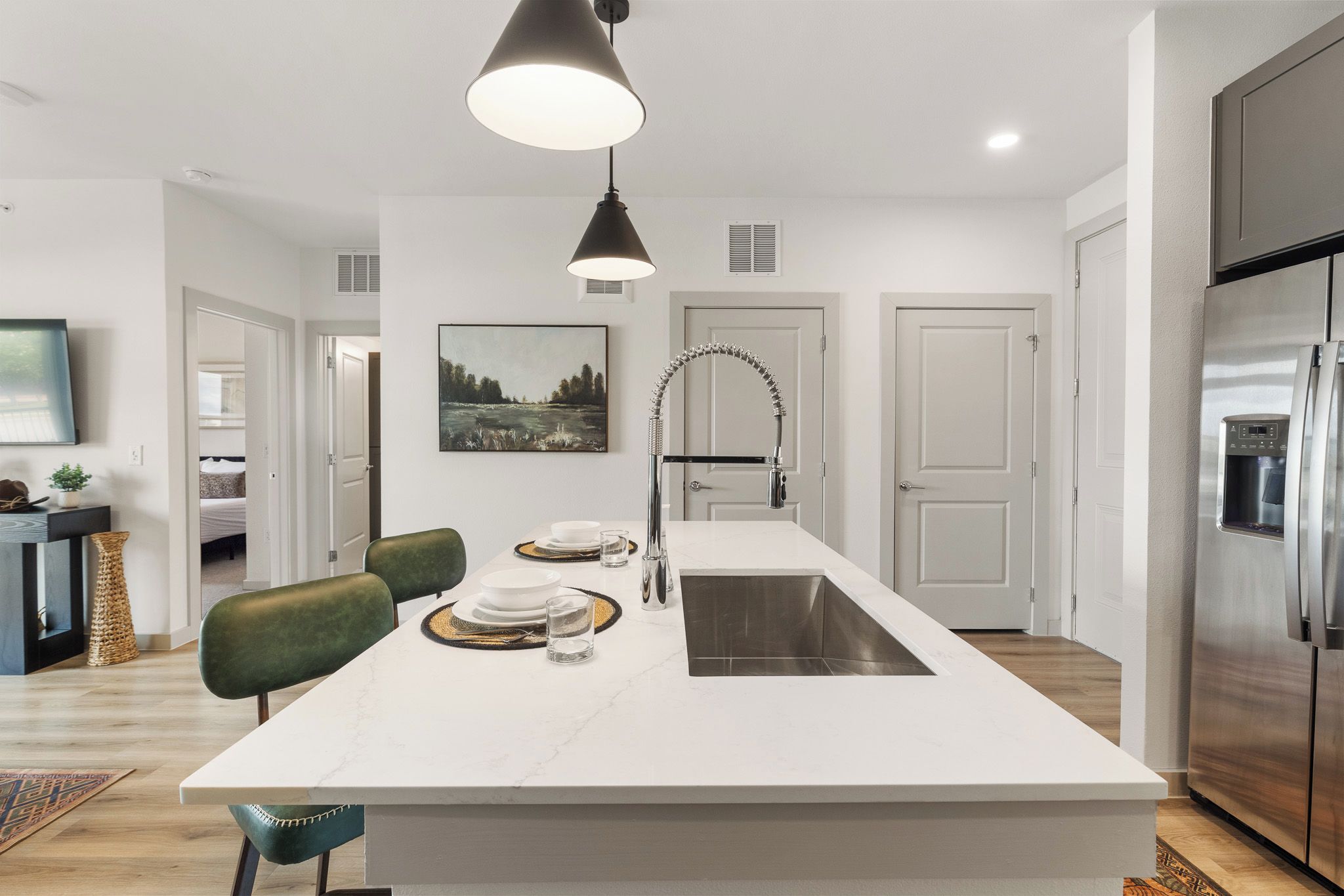 A modern kitchen with a central island, stainless steel appliances, and a pendant light.