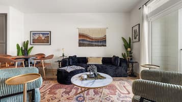 Een zithoek met een donkerblauwe bank, een ronde salontafel en een kamerbreed tapijt.