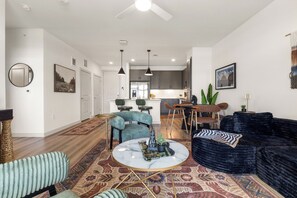 Een moderne woonkamer met een marmeren bijzettafeltje, een zwarte veloursbank en een kamerbreed tapijt met een patroon.