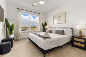 Een hotelkamer met een groot bed, een nachtkastje, een lamp, een ingelijste foto aan de muur en uitzicht.