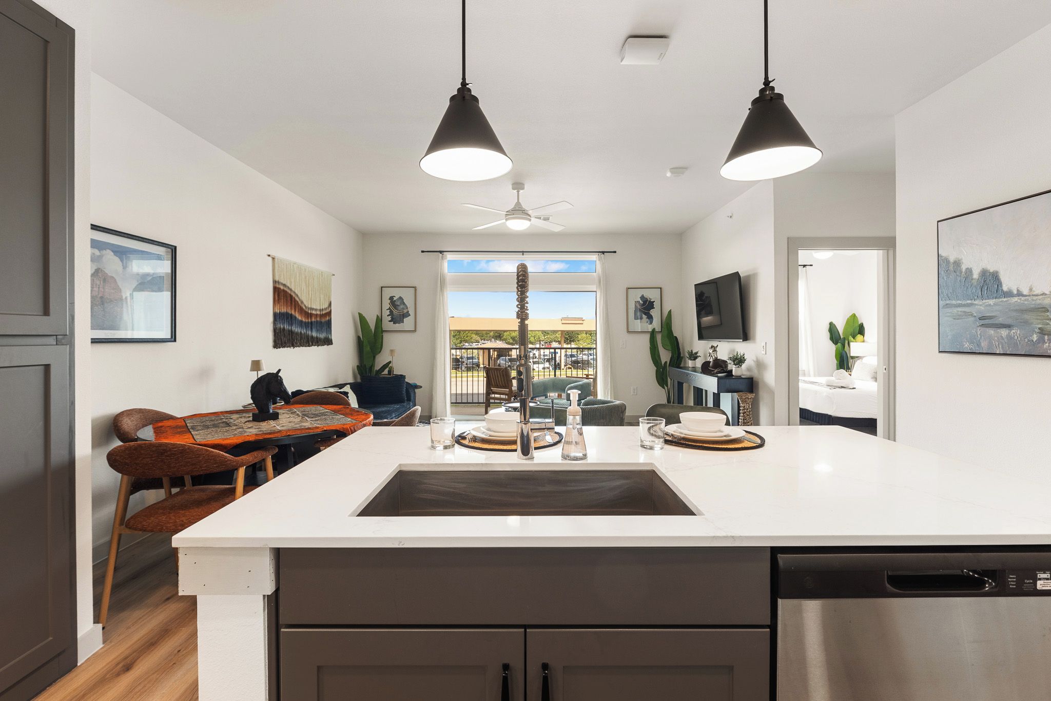 A modern kitchen with a central island, pendant lighting, and a view to the outside.