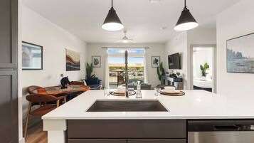 A modern kitchen with a central island, pendant lighting, and a view to the outside.