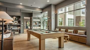 A spacious living room with a pool table, a sofa, and a bookshelf.