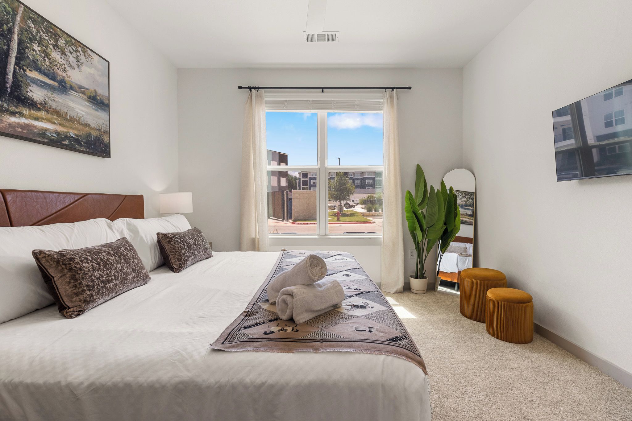 Una habitación de hotel con una cama grande, vistas al exterior y una planta en maceta.