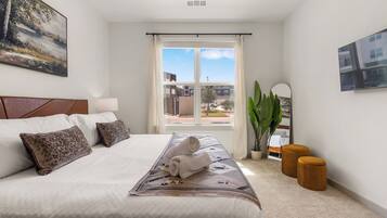 Una habitación de hotel con una cama grande, vistas al exterior y una planta en maceta.