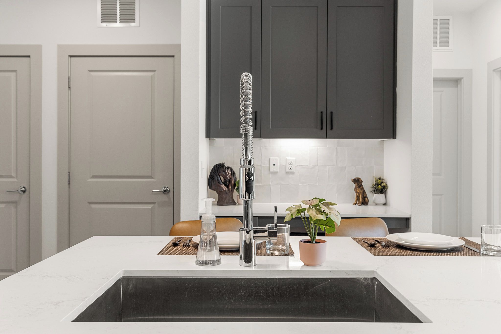 Una cocina moderna con una isla central, un grifo de acero inoxidable y un lavabo negro.