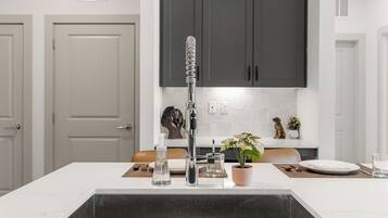 Una cocina moderna con una isla central, un grifo de acero inoxidable y un lavabo negro.