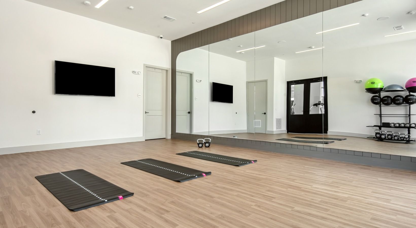 Un gimnasio con colchonetas de ejercicio, cinta de correr y un soporte para pesas.