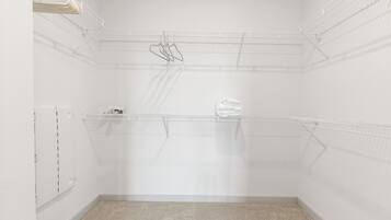 A small, empty walk-in closet with a metal shelving unit, a white door, and a carpeted floor.