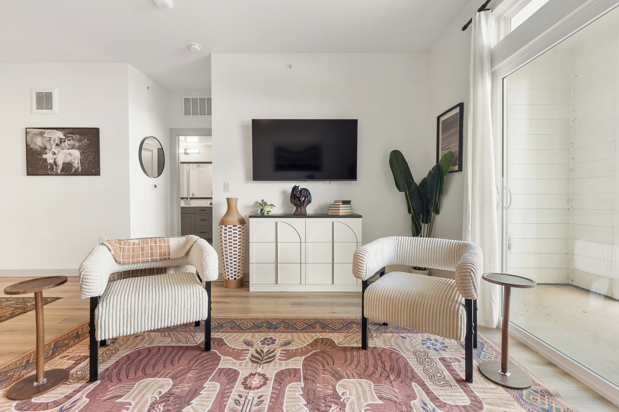 A modern living room with a sofa, a coffee table, a TV, and a large window.
