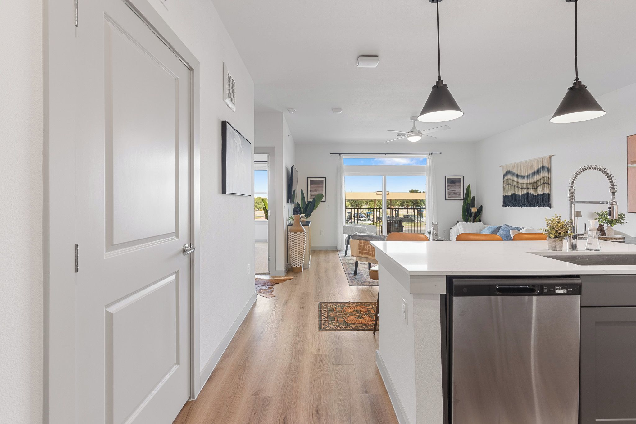 A modern kitchen with a dishwasher, a dining area with a bench, and a view to the outside.